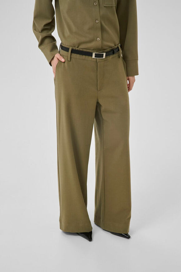 Wide-leg pants feature a tailored fit and crisp appearance with a straight waistband and subtle crease. Minimalistic details and belt loops offer a polished look, versatile for styling. Secure zipper fly with no visible pockets.